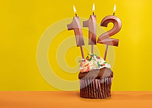 Candle with flame number 112 - Birthday card on yellow background