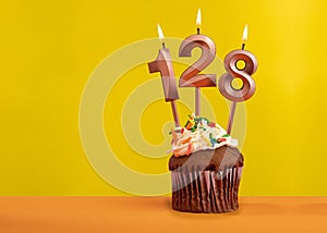 Candle with flame number 128 - Birthday card on yellow background