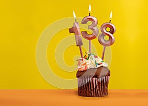 Candle with flame number 138 - Birthday card on yellow background