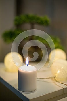 Candle in front of Bonsai tree on white table in bedroom