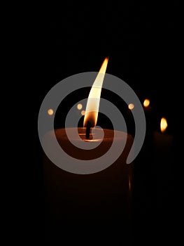 A Candle in front ot more candles, in the dark