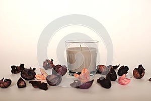 Candle in a glass around flower petals photo