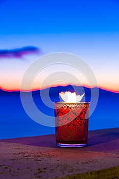 Candle glass at sunset in italy, sea and Elba island, in the background