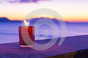 Candle glass at sunset in italy, sea and Elba island, in the background