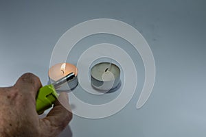 Candle and green lighter with hand on white background