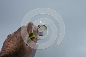 Candle and green lighter with hand on white background