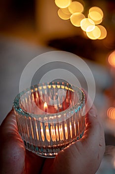 candle in the hands of a woman in a hand on a background of a burning candles