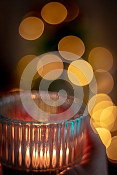 candle in the hands of a woman in a hand on a background of a burning candles