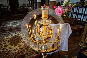 Candle holder with lit candles and flowers inside the church of Sveta Troitsa Holy Trinity in Dryanovo Bulgaria.