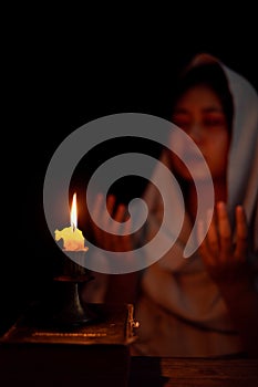 Candle light with blur young girl praying in dark night background. Woman person worship God with faith and belief. religion,