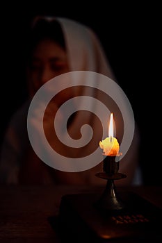 Candle light with blur young girl praying in dark night background. Woman person worship God with faith and belief. religion,