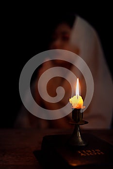 Candle light with blur young girl praying in dark night background. Woman person worship God with faith and belief. religion,