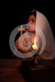 Candle light with blur young girl praying in dark night background. Woman person worship God with faith and belief. religion,