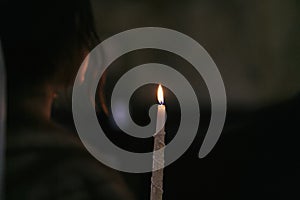 Candle light in the dark in church. bride holding candle fire during holy matrimony in church. atmospheric spiritual moment.