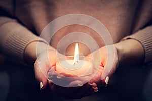 Candle light glowing in woman's hands. Praying, faith, religion