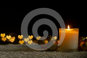 Candle lights and Christmas ornaments with golden love shape bokeh lights.