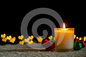 Candle lights and Christmas ornaments with golden love shape bokeh lights.