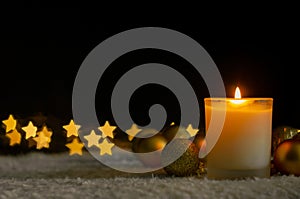 Candle lights and Christmas ornaments with golden star shape bokeh lights.