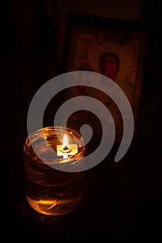 Candle lights with flame glowing on oil in the interior of a church. Symbol of faith and spirit