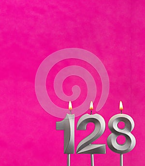 Candle number 128 - Birthday celebration on fuchsia background