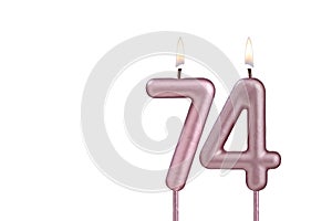 Candle number 74 - Lit birthday candle on white background