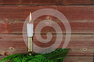 Candle at old barn wall and green decoration