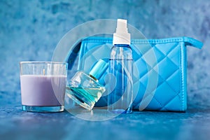 Candle perfume and cosmetic bag in shallow depth of field on blue background