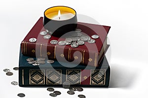 Candle with Silver Coins & Books on White Background