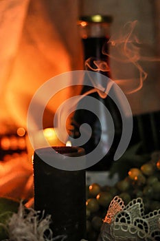 Candle smoke extinct on table with bottle of red wine, grape and soft flamelight on sackcloth background. Soulful autumn