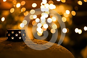 A candle on the snow in the night with boche background.