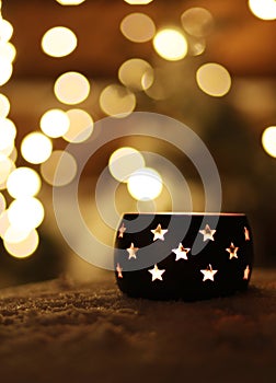 A candle with stars on the snow in the night with boche background.