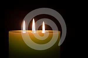 Candle with three flames on black background
