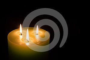 Candle with three flames on black background