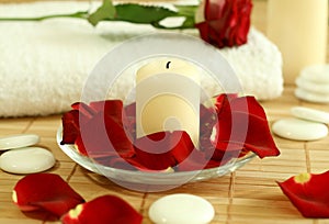 Candle, towel and petals of red rose.