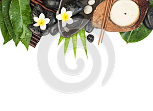 Candle, towel, stones, and flowers with tropical leaves