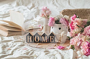 Candle and Vase with roses and peonies flowers and spring decor on the books