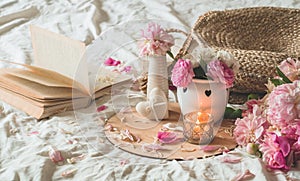 Candle and Vase with roses and peonies flowers and spring decor on the books