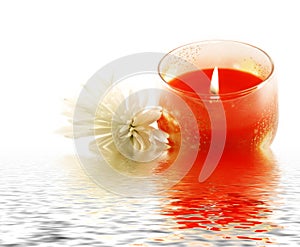 Candle and white flower reflecting in water