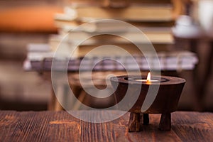 Candle on wooden table with books in background