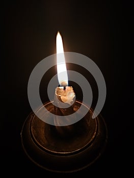 Burning candle in a candlestick on a black background