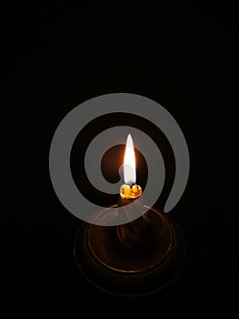 Burning candle in a candlestick on a black background
