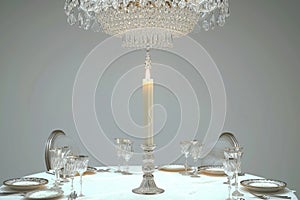 A candlelit dinner setting with an elegant crystal chandelier hanging above a round table.