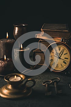 Candles,  antique books, old clock and old rusty keys in vintage style