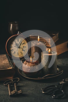 Candles,  antique books, old clock and old rusty keys in vintage style