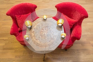 Candles on a antique side table with intarsia and red chair