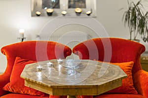 Candles on a antique side table with intarsia and red chair