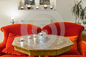 Candles on a antique side table with intarsia and red chair