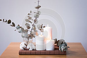 Candles and branches of eucalyptus on table