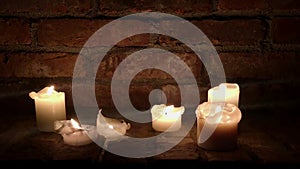 Candles burn in the dark on a brick wall background
