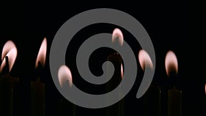 Candles burn in a dark temple. Black background. Close up